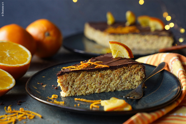 Orangen-Mandel-Kuchen auf Keramikteller mit Orangedeko