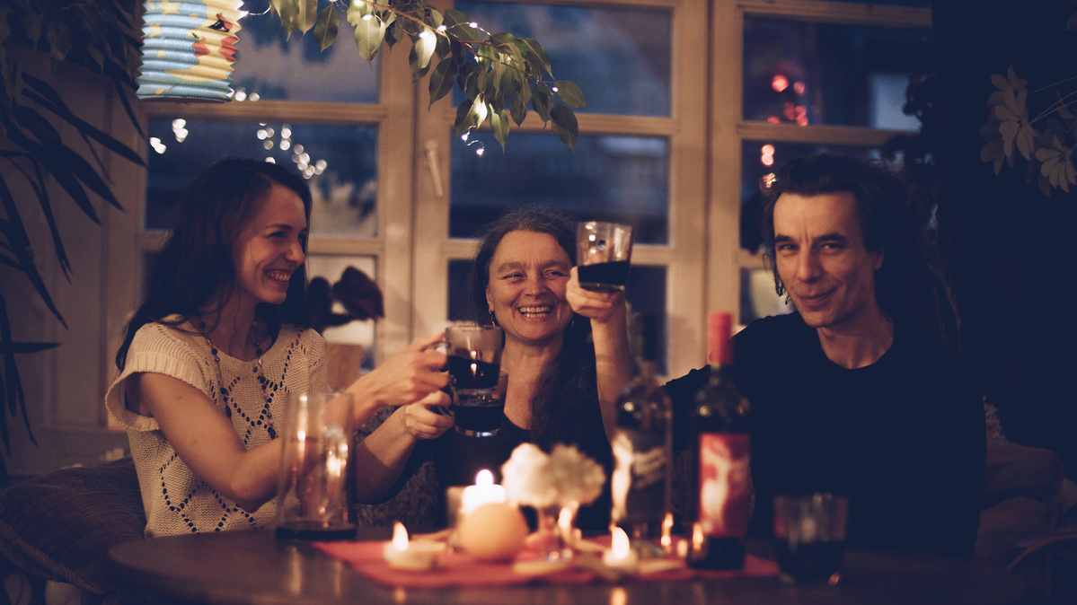 Drei Menschen in stimmungsvoller Atmosphäre prosten sich mit Glühwein zu