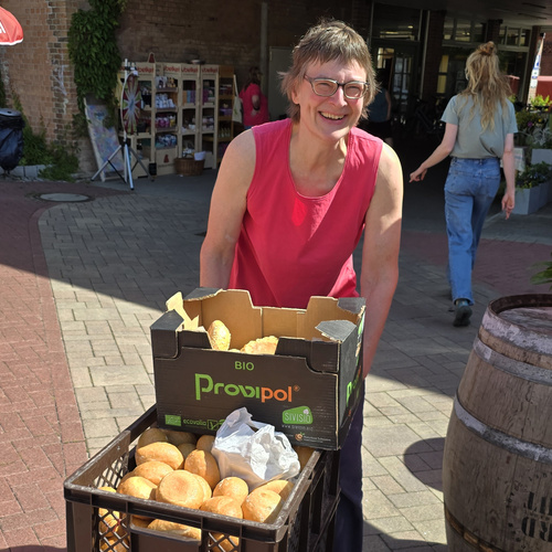 KI generiert: Person mit Brot in Kisten lächelnd draußen; Text: "BIO Provipol".