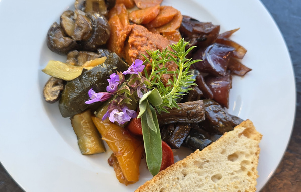 KI generiert: Ein Teller mit gebratenem Gemüse, Brot und Kräutern dekoriert.