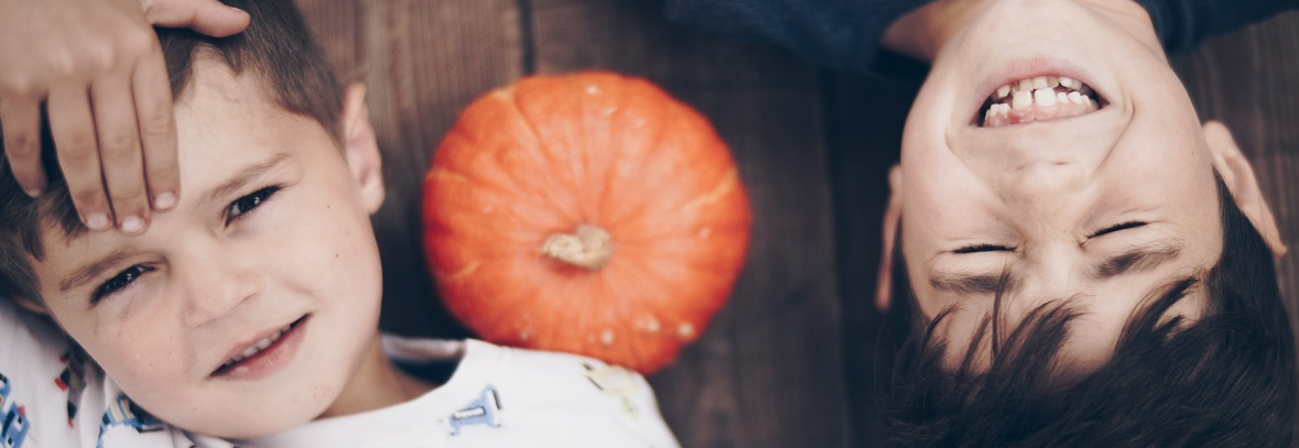 Grünland zwei Kindergesichter mit Hokkaido-Kürbis in der Mitte