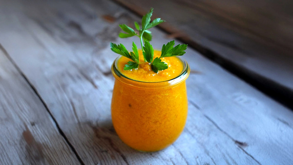 KI generiert: Oranges Smoothie im Glas mit Petersilie garniert auf Holztisch.