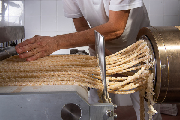 KI generiert: Eine Person bedient eine Maschine zur Herstellung von Pasta.