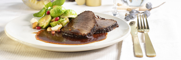Weihnachtsbraten auf Porzellanteller auf festlich gedecktem Tisch