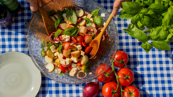 Kleine Gläser mit buntem Krautsalat, garniert mit essbaren Blüten und Kräutern, auf einem Tisch drapiert.